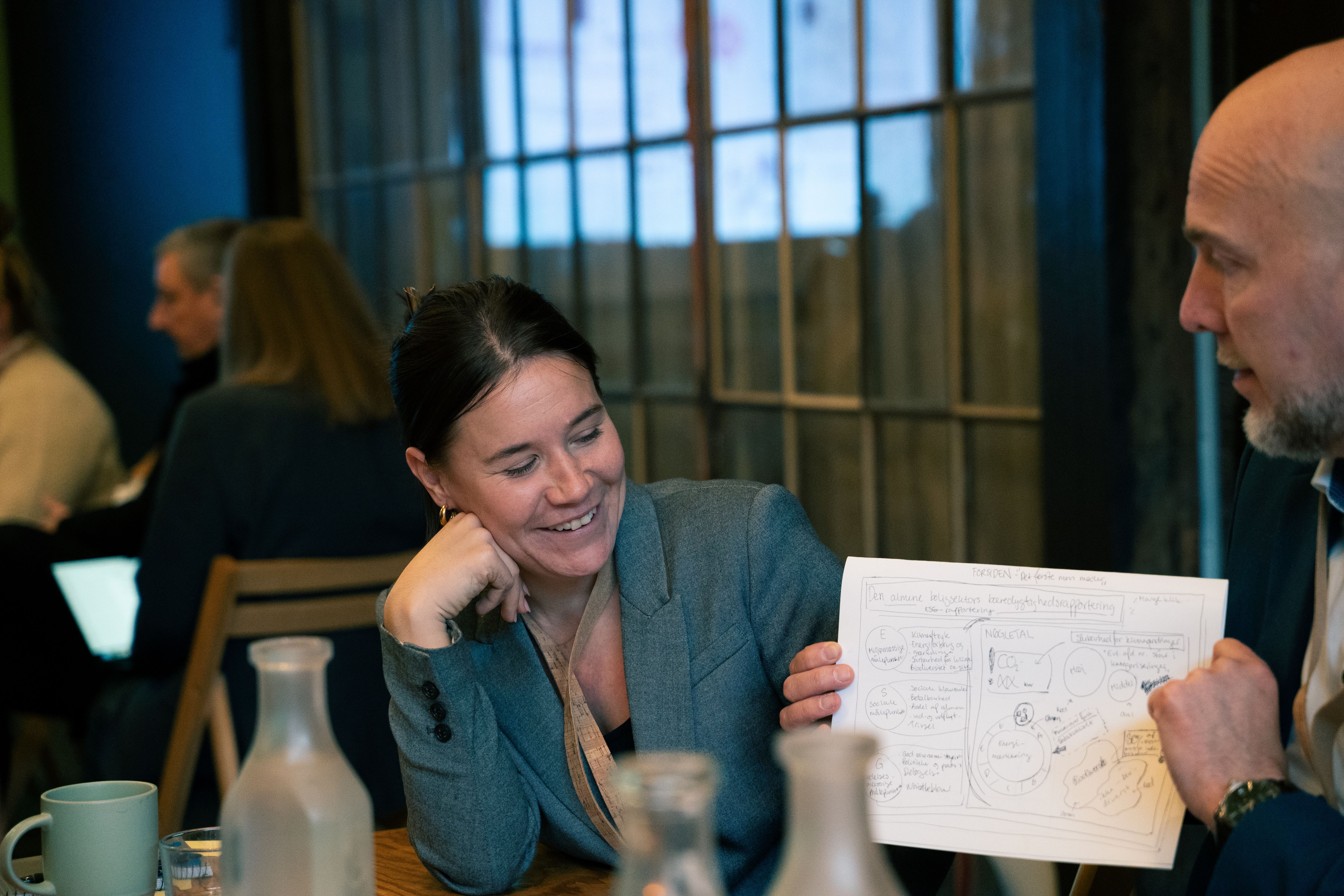 En kvinde kigger på en tegning, som en mand holder op - til designworkshop 