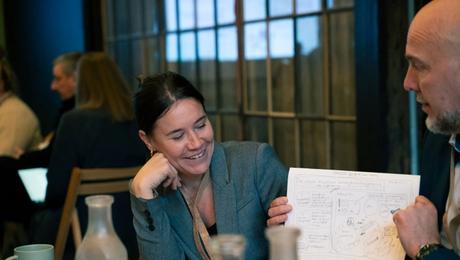 En kvinde kigger på en tegning, som en mand holder op - til designworkshop