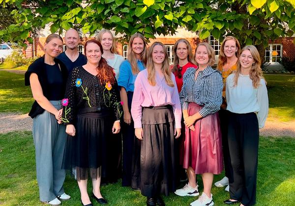 Gruppebillede med 10 personer i grønne omgivelser