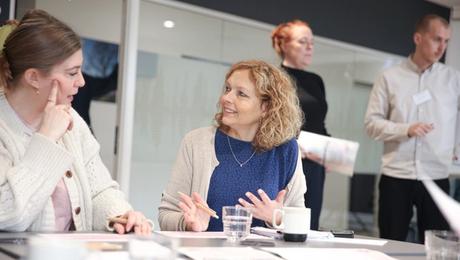 To kvinder i drøftelse ved bord med papirer