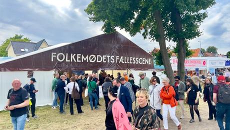Stort debattelt med teksten "Folkemødets fællesscene". Mennesker i bevægelse foran teltet.