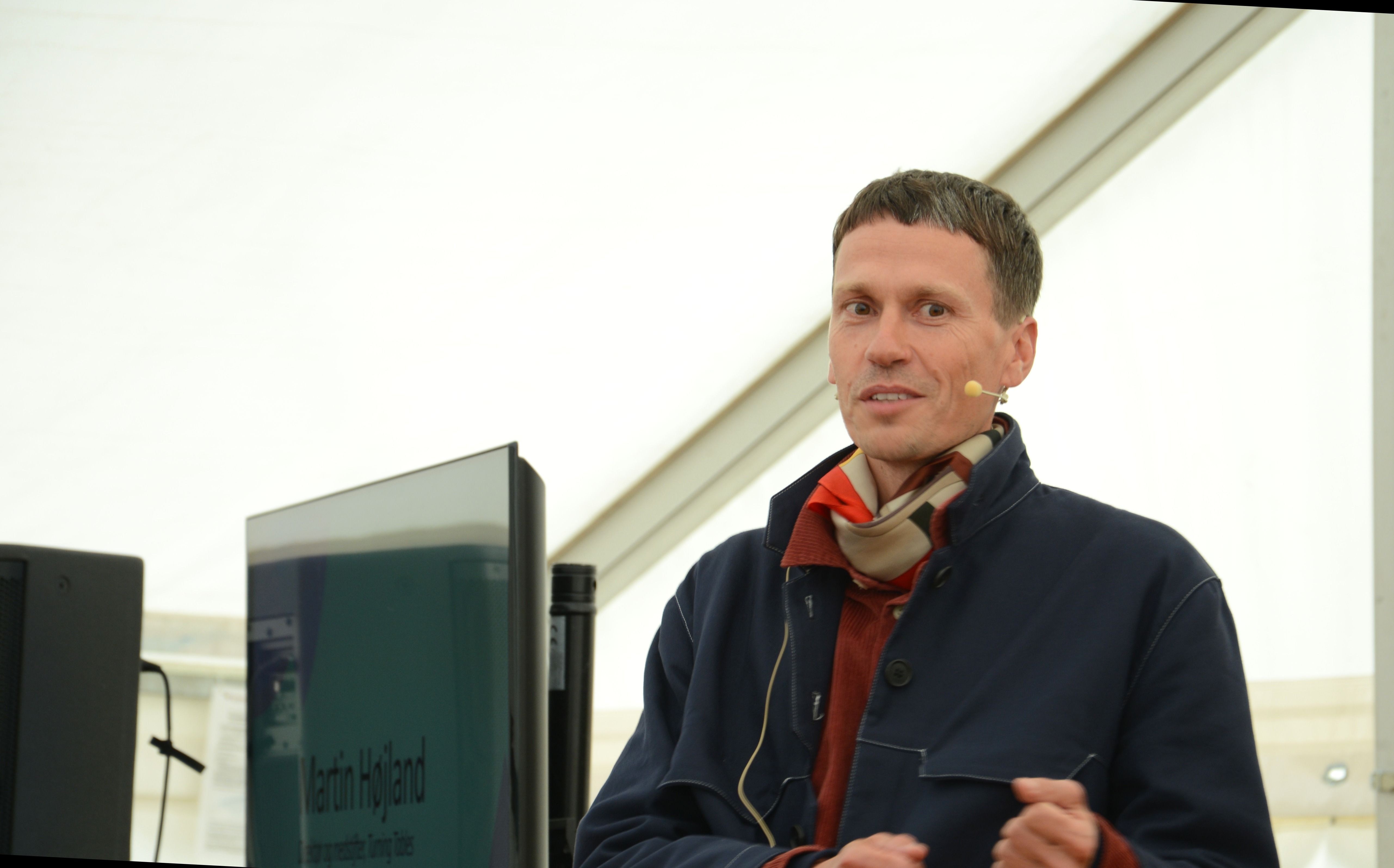 Closeup af mand med mikrofon i telt med skærm ved siden af