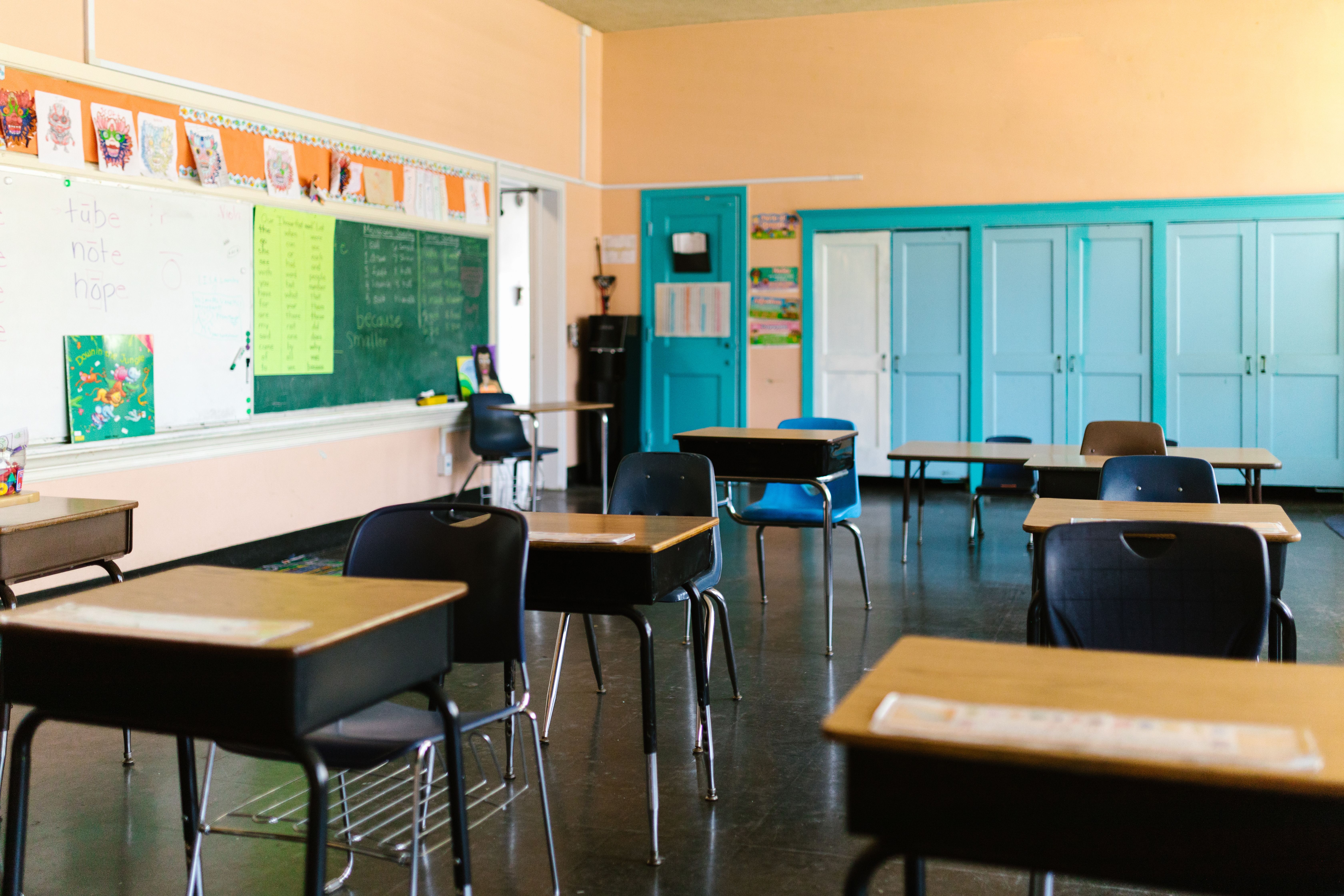 Empty classroom with desks, blackboard and educational materials