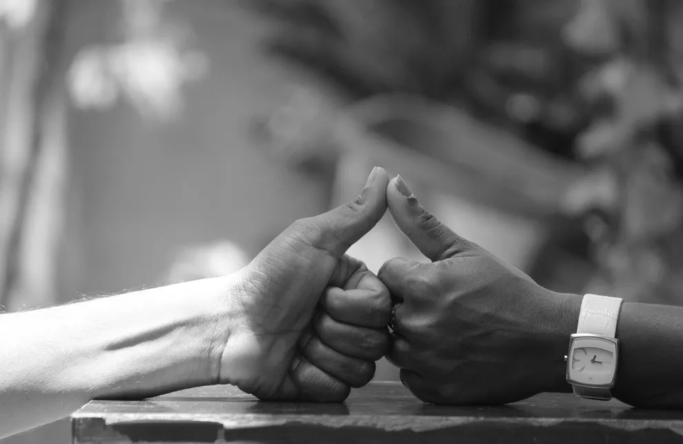 Two hands giving thumbs up, one light-skinned, one dark-skinned.