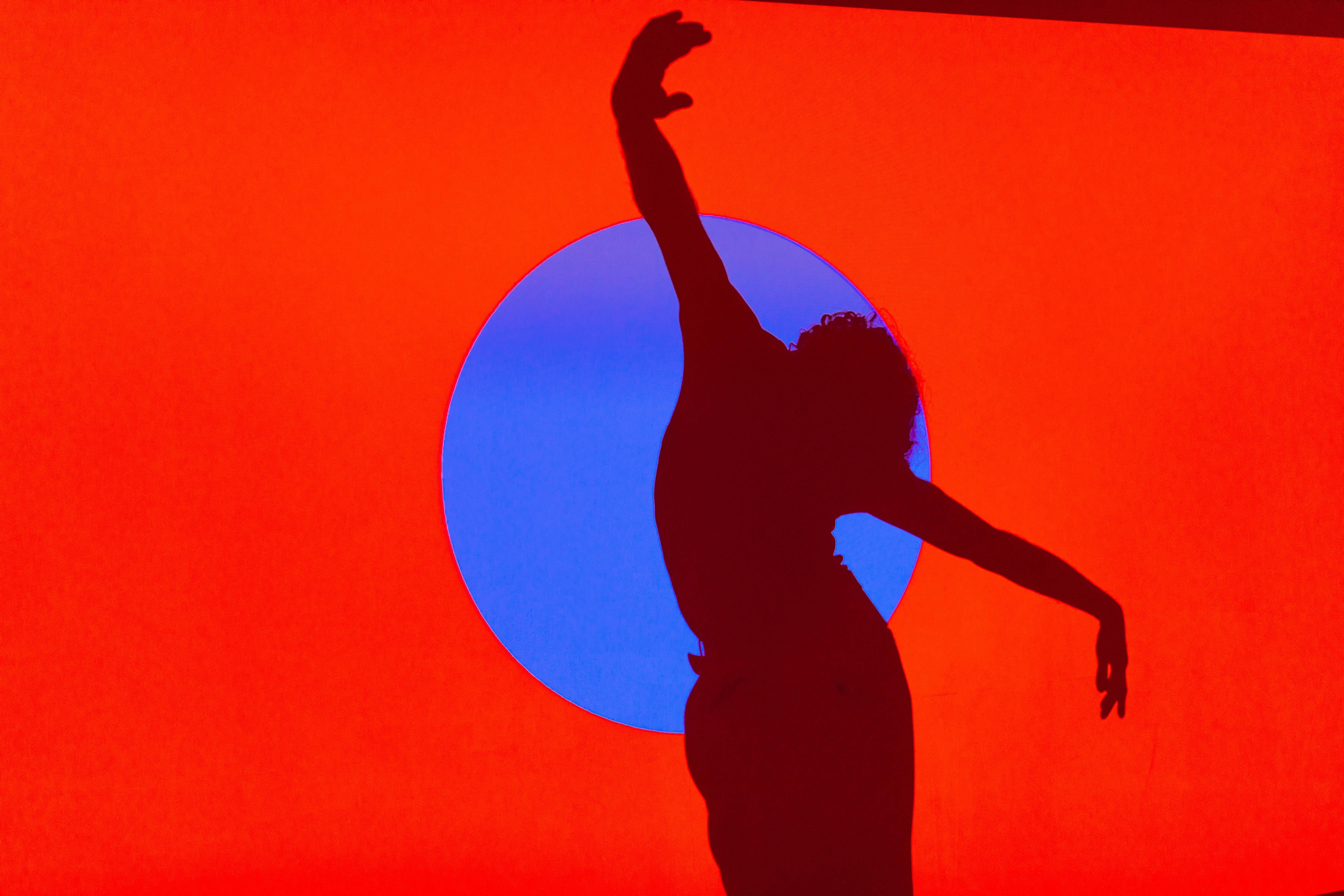 Silhouette of a person dancing in orange background