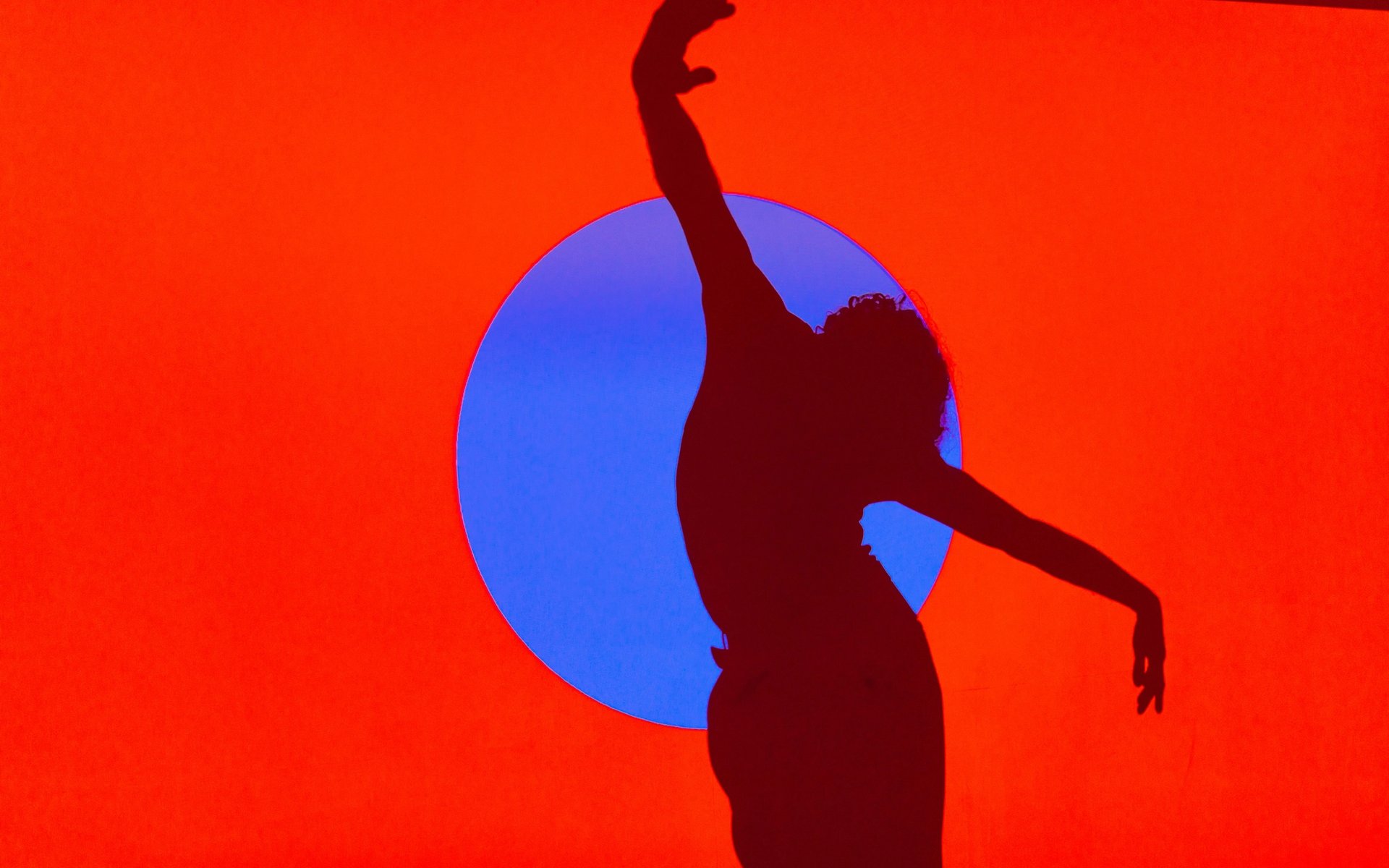 Silhouette of a person dancing in orange background