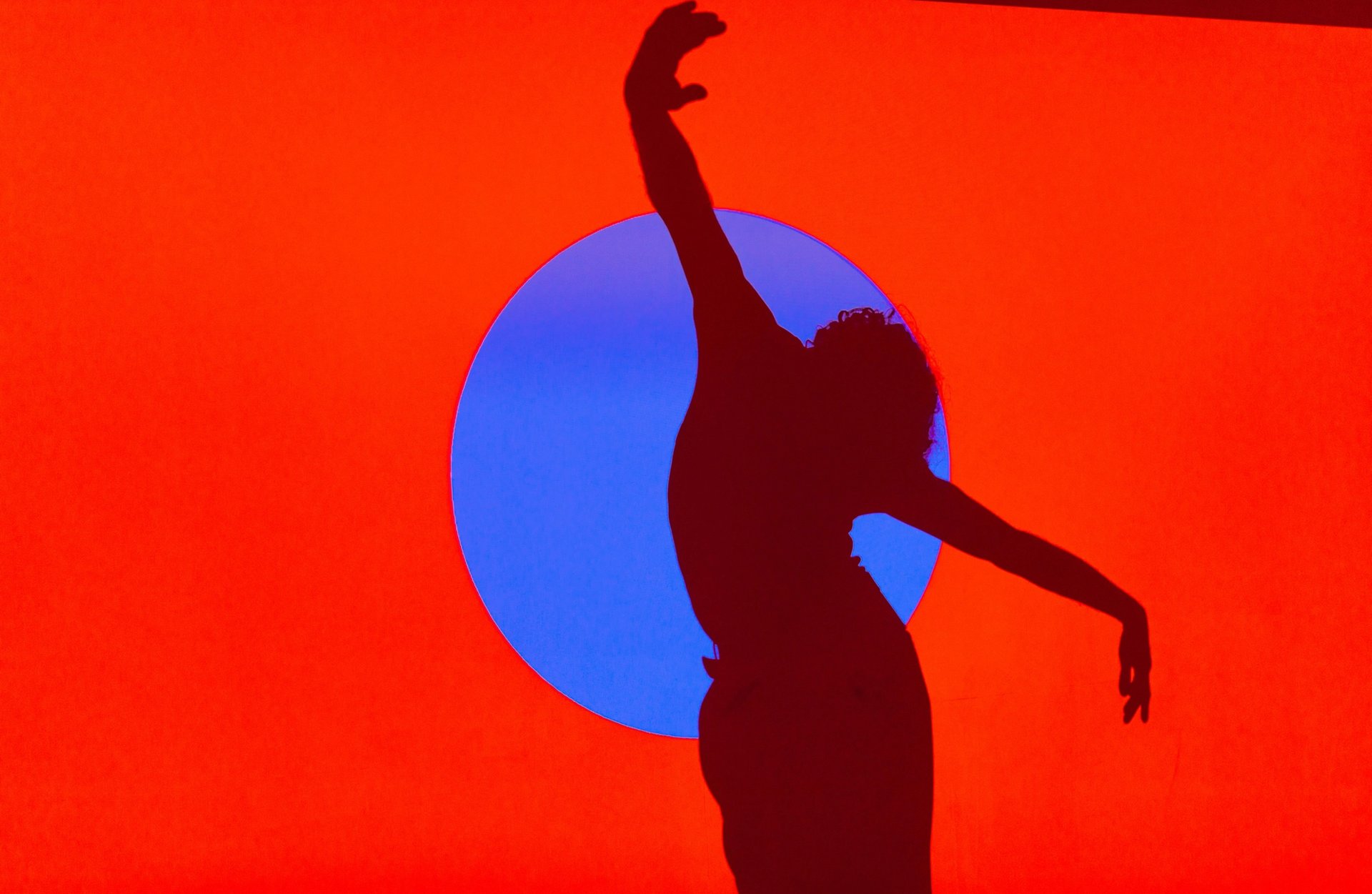 Silhouette of a person dancing against an orange background