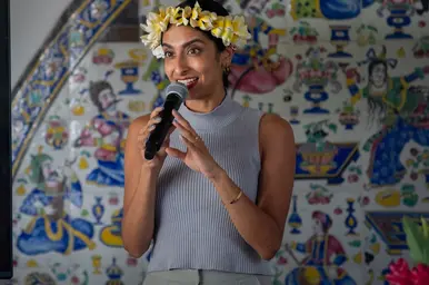 Artist holds a microphone in front of a screen with the word “COMEDY” in bright colors.