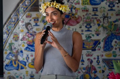 Artist holds a microphone in front of a screen with the word “COMEDY” in bright colors.