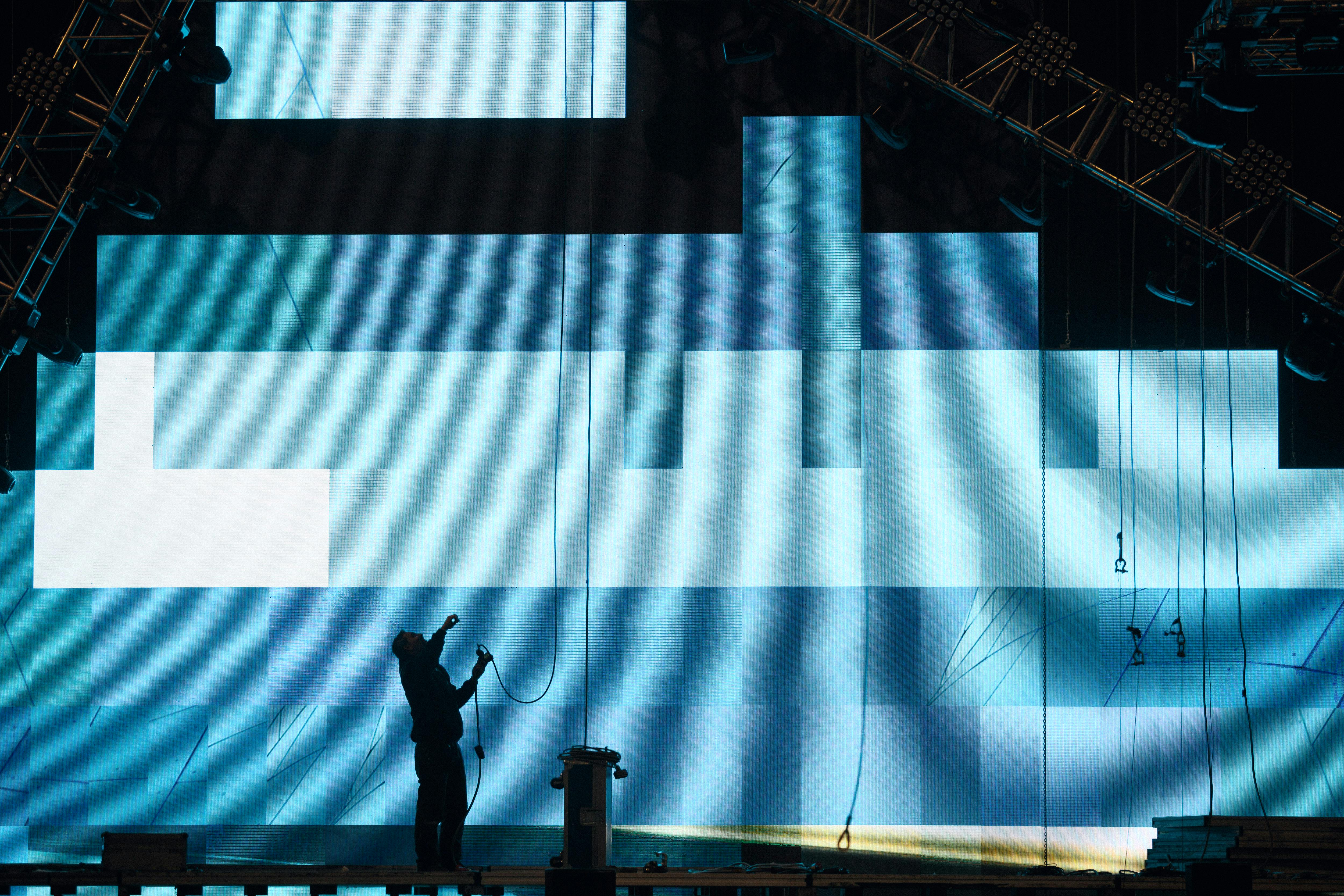 Silhouette of a person installing digital screen on stage