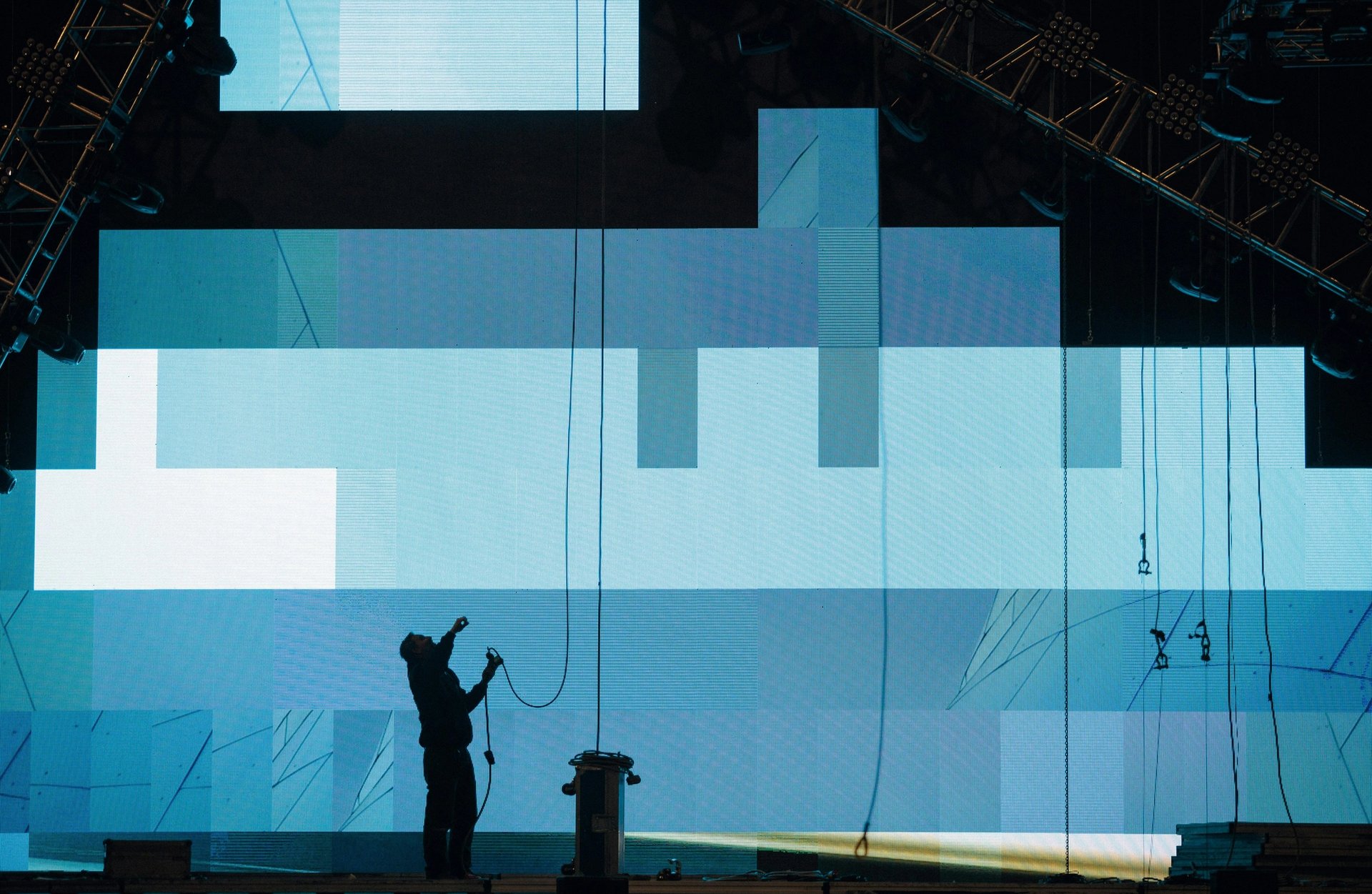 Silhouette of a person installing digital screen on stage