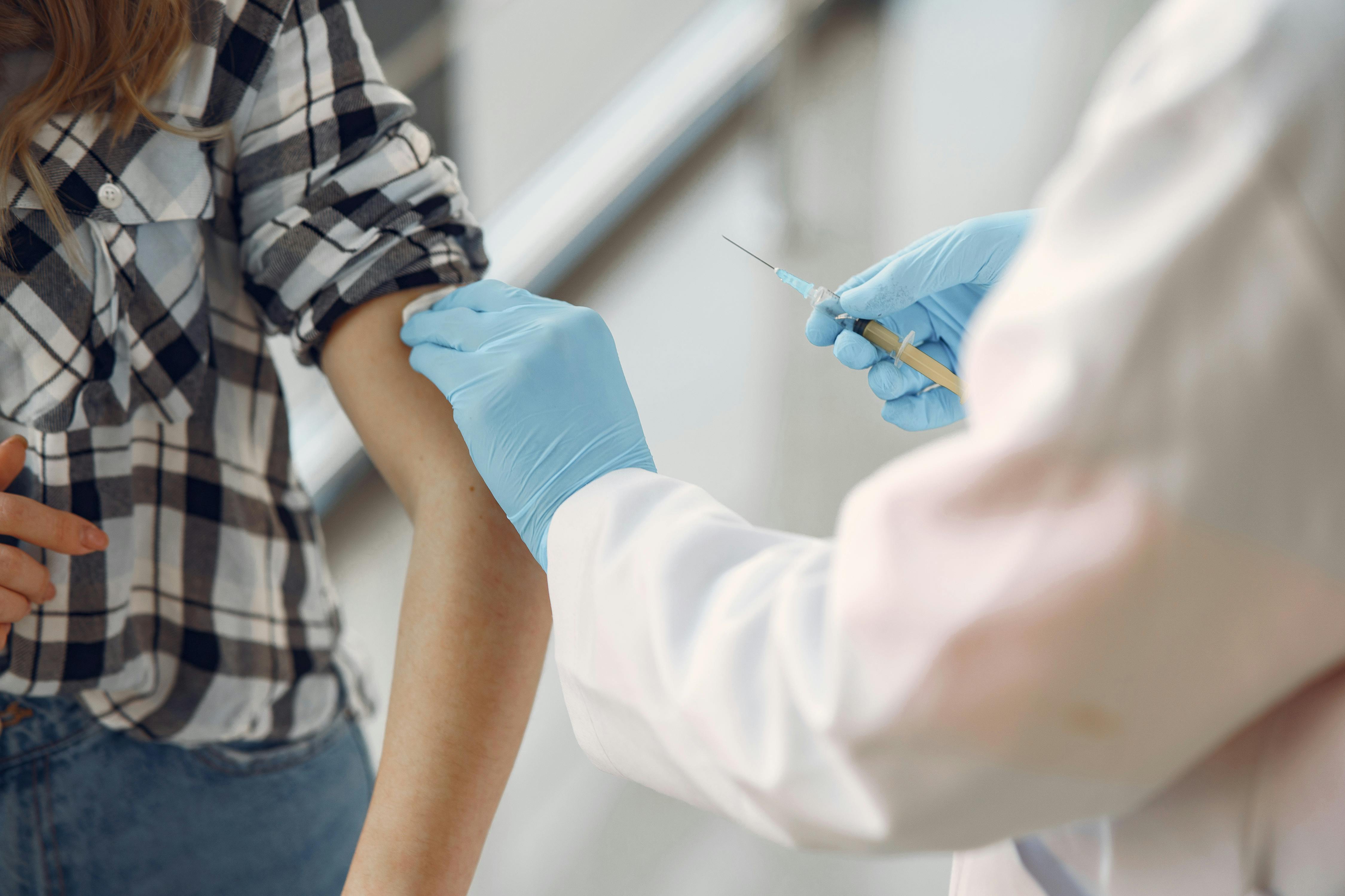 Healthcare professional wearing blue gloves prepares to administer a vaccine.