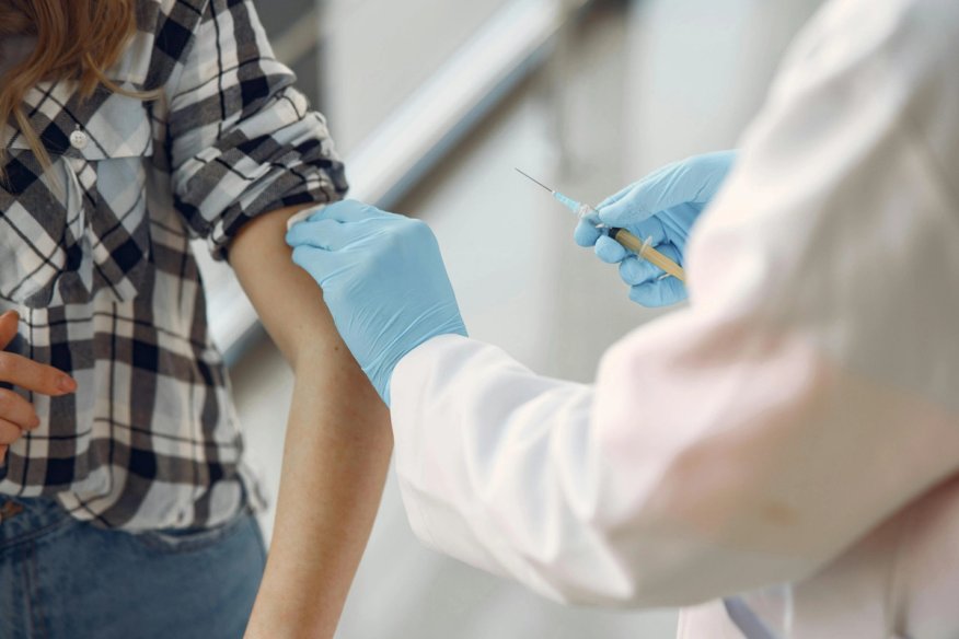 Healthcare professional wearing blue gloves prepares to administer a vaccine.