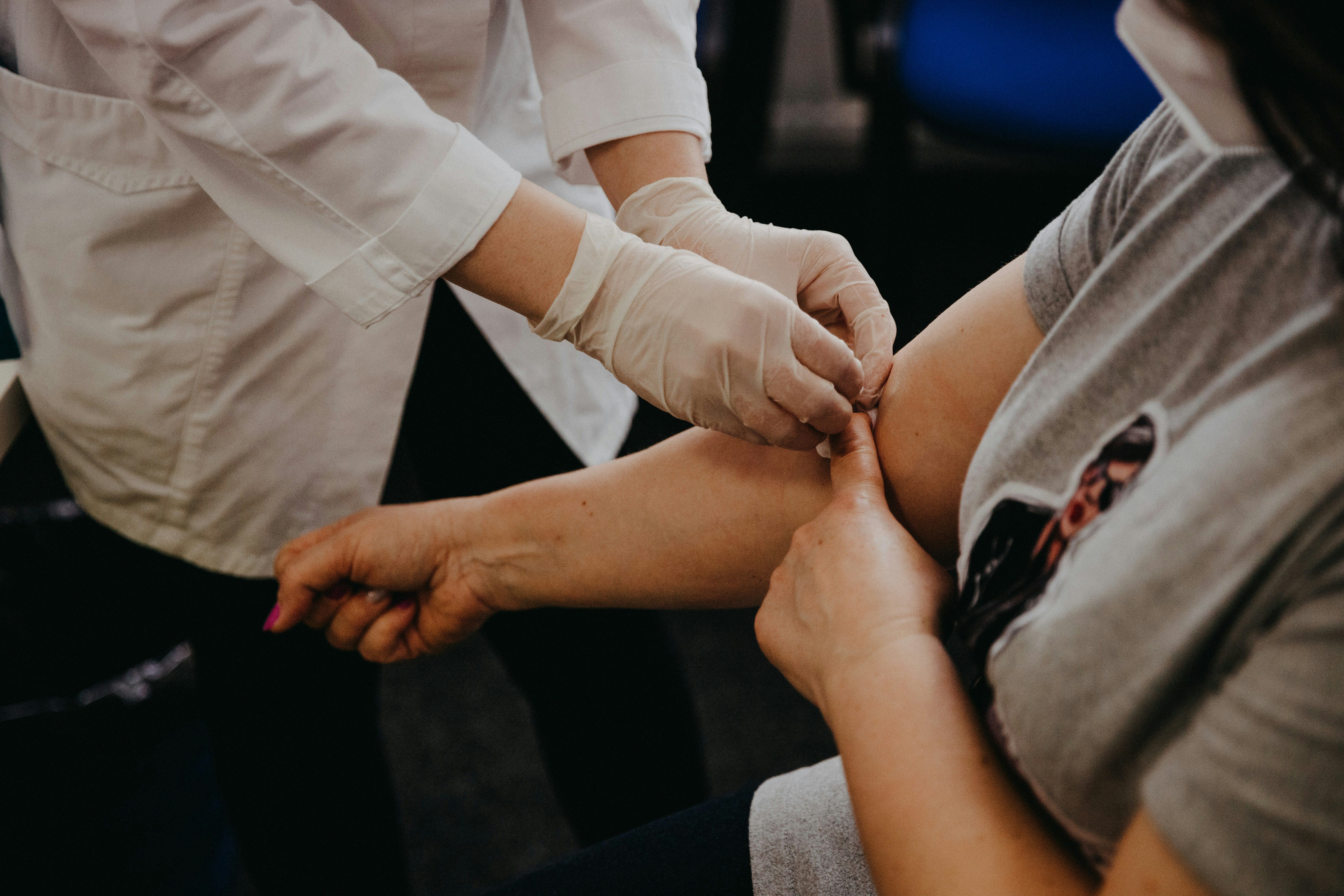 Healthcare worker in gloves administers a vaccine to a patient’s upper arm.