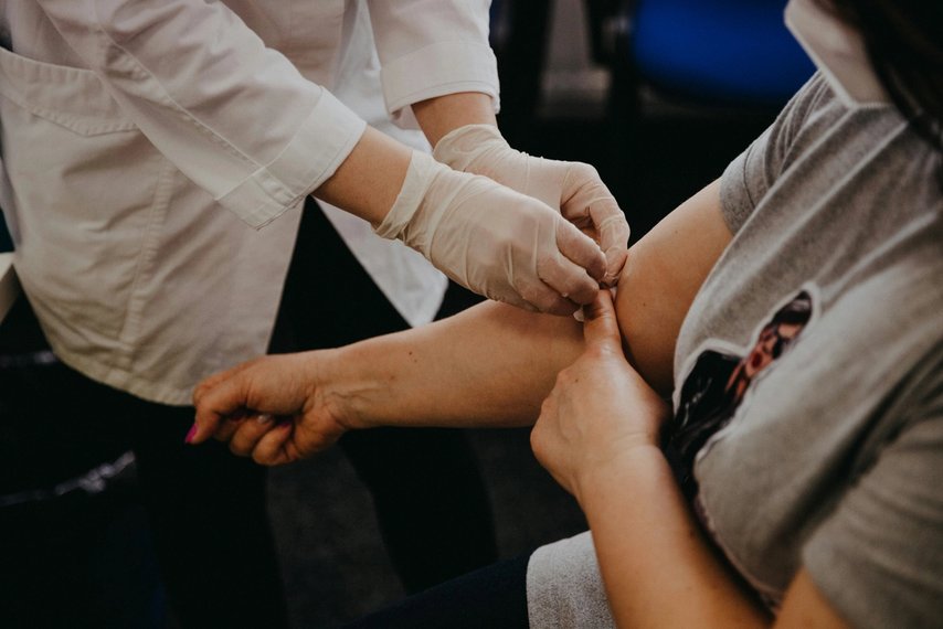 Healthcare worker in gloves administers a vaccine to a patient’s upper arm.
