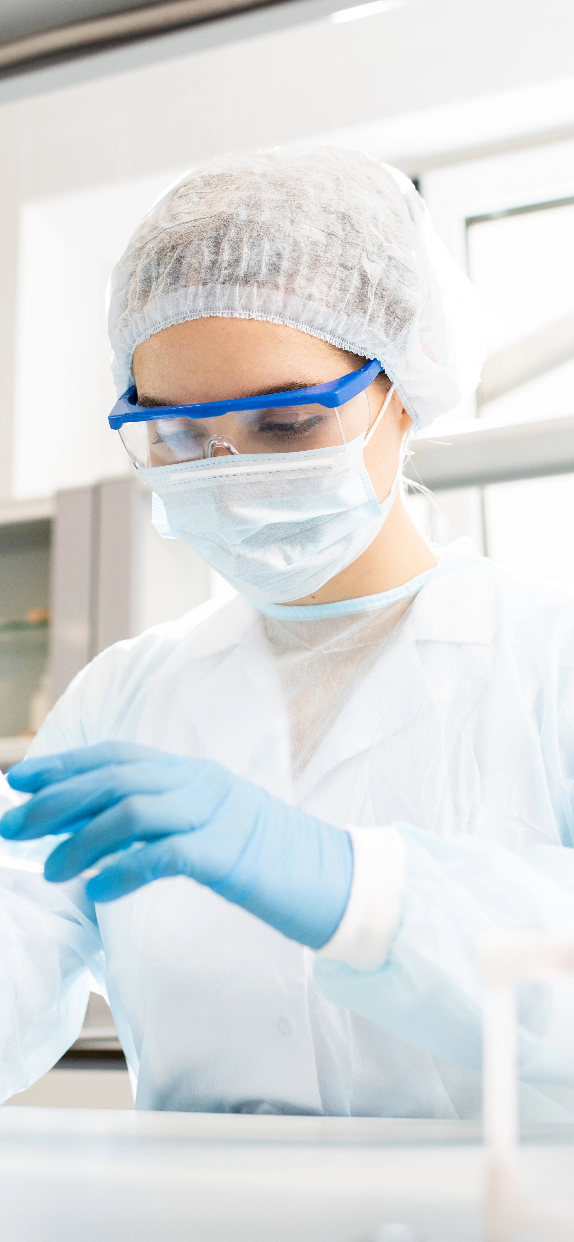 Scientist in a full protective lab suit and goggles uses a pipette in a research lab.