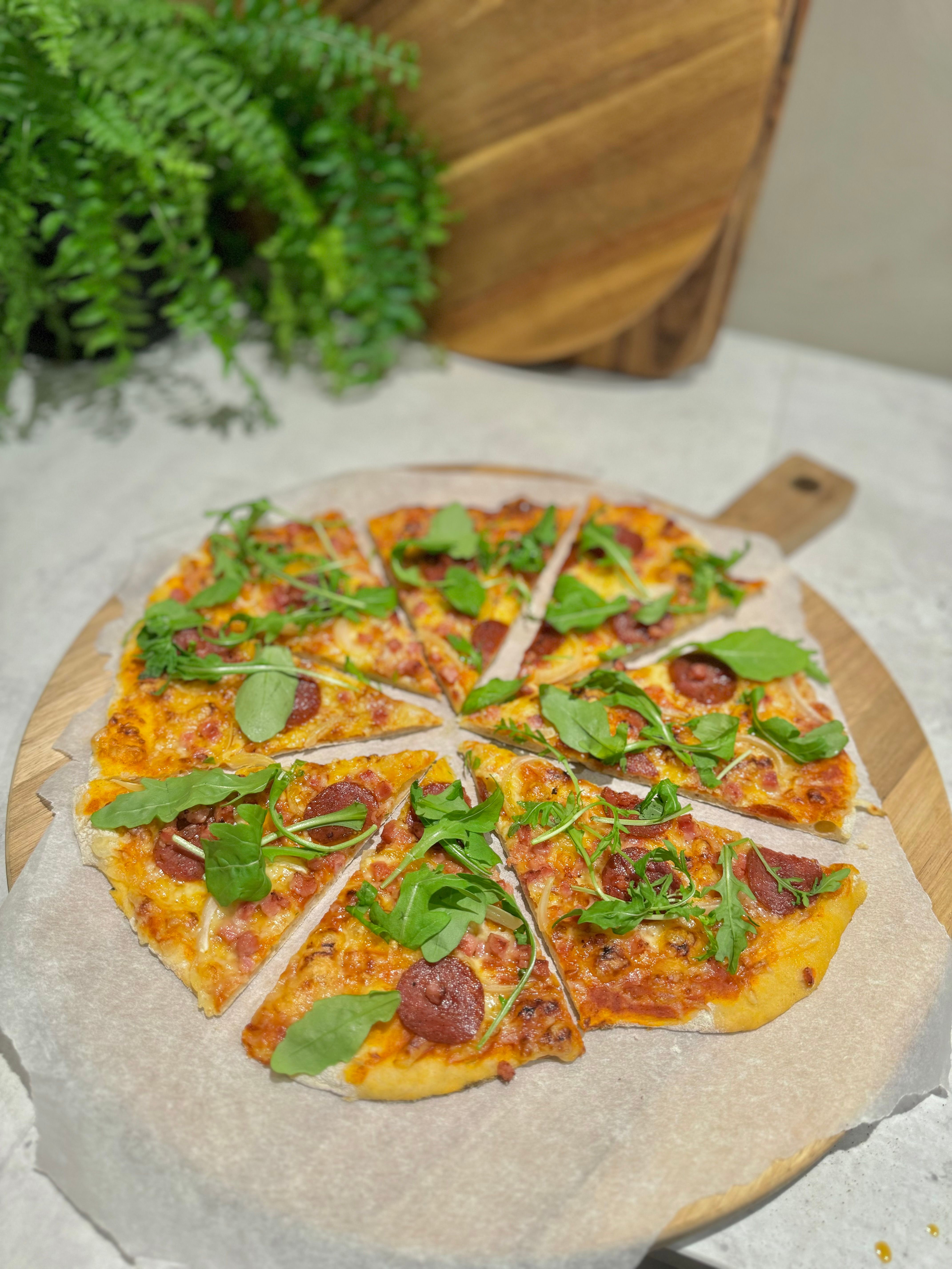 Tynn, sprø speltpizza med pepperoni, bacon & løk