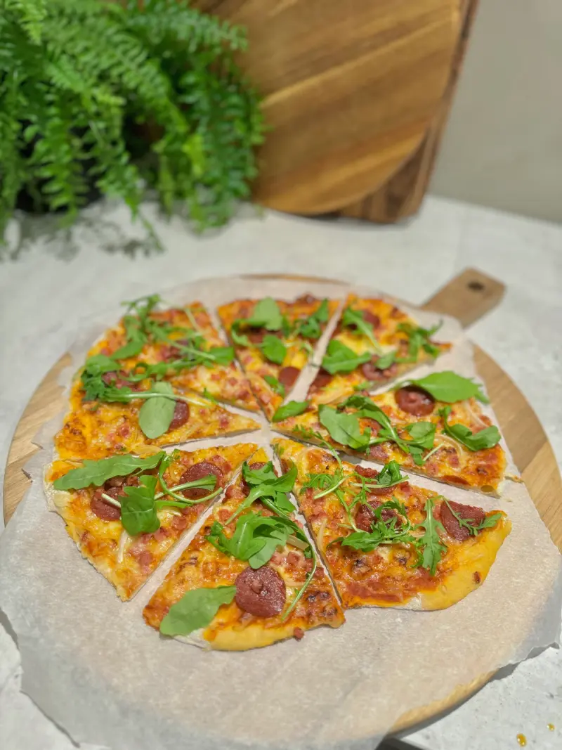 Tynn, sprø speltpizza med pepperoni, bacon & løk