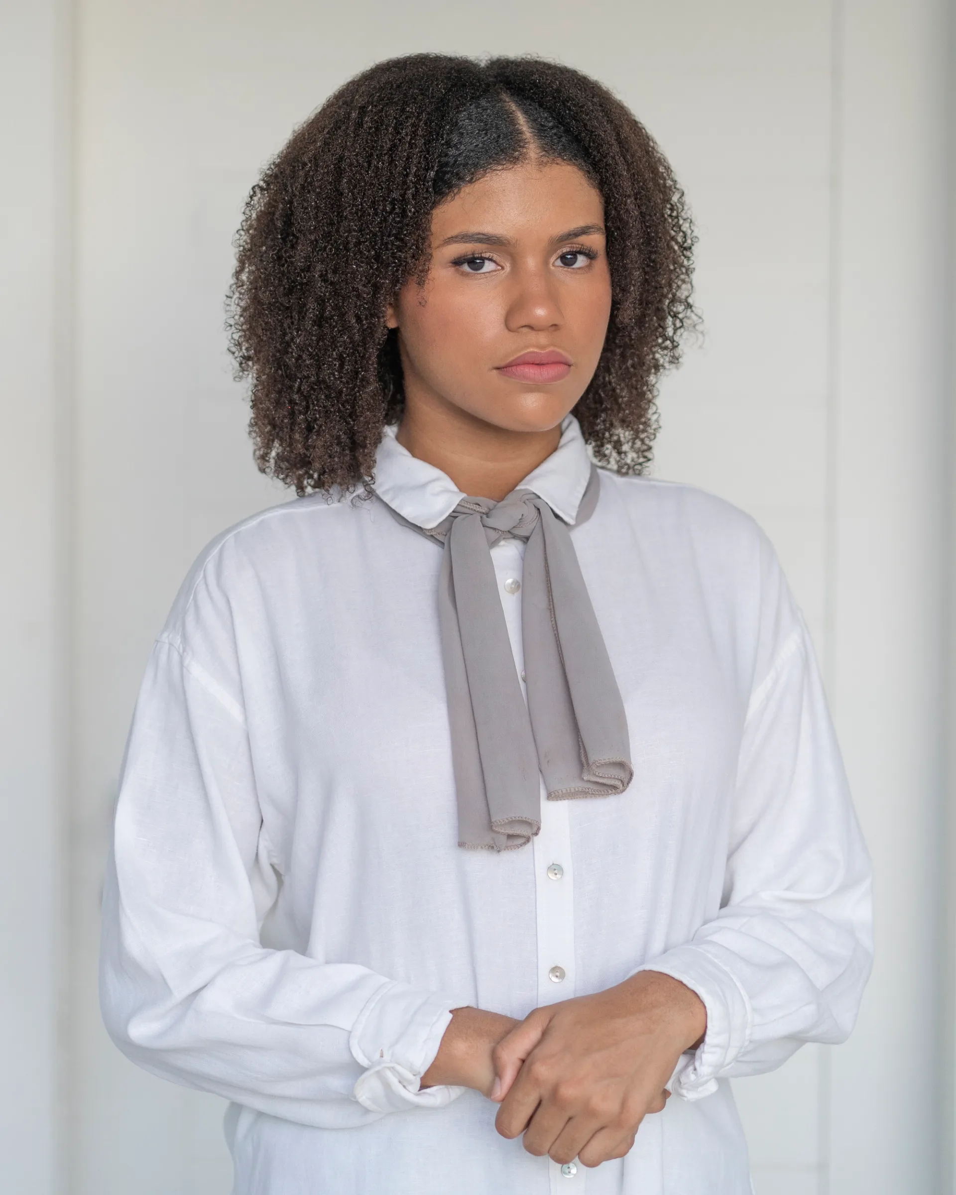 Woman with a curly hair posed against a neutral background