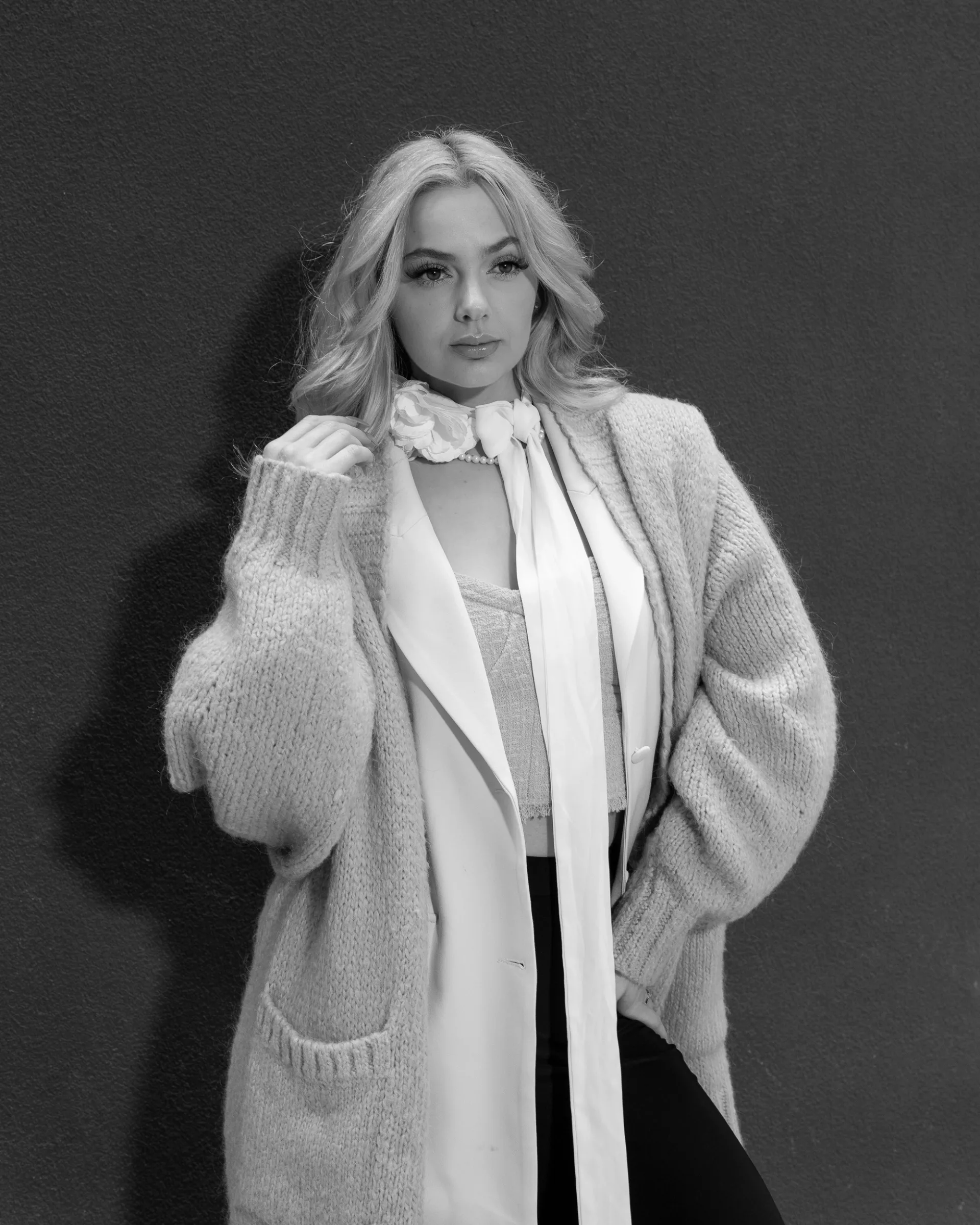 Fasion model in a black and white editorial portrait, styled in layered knitwear with a confident pose 