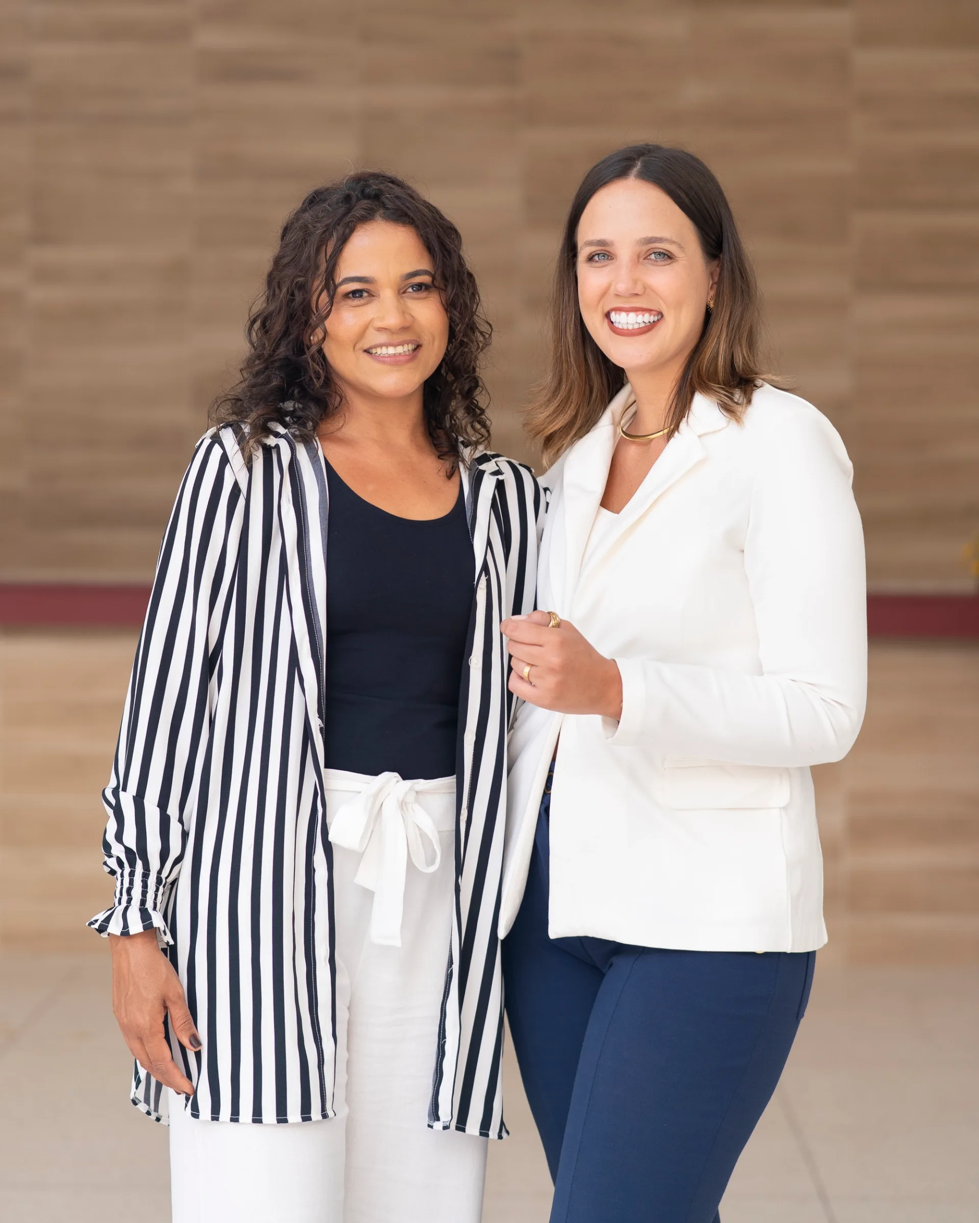 PROFESSIONAL BRANDING PORTRAIT OF TWO WOMEN SMILING TOGETHER IN A MODERN BUSINESS SETTING