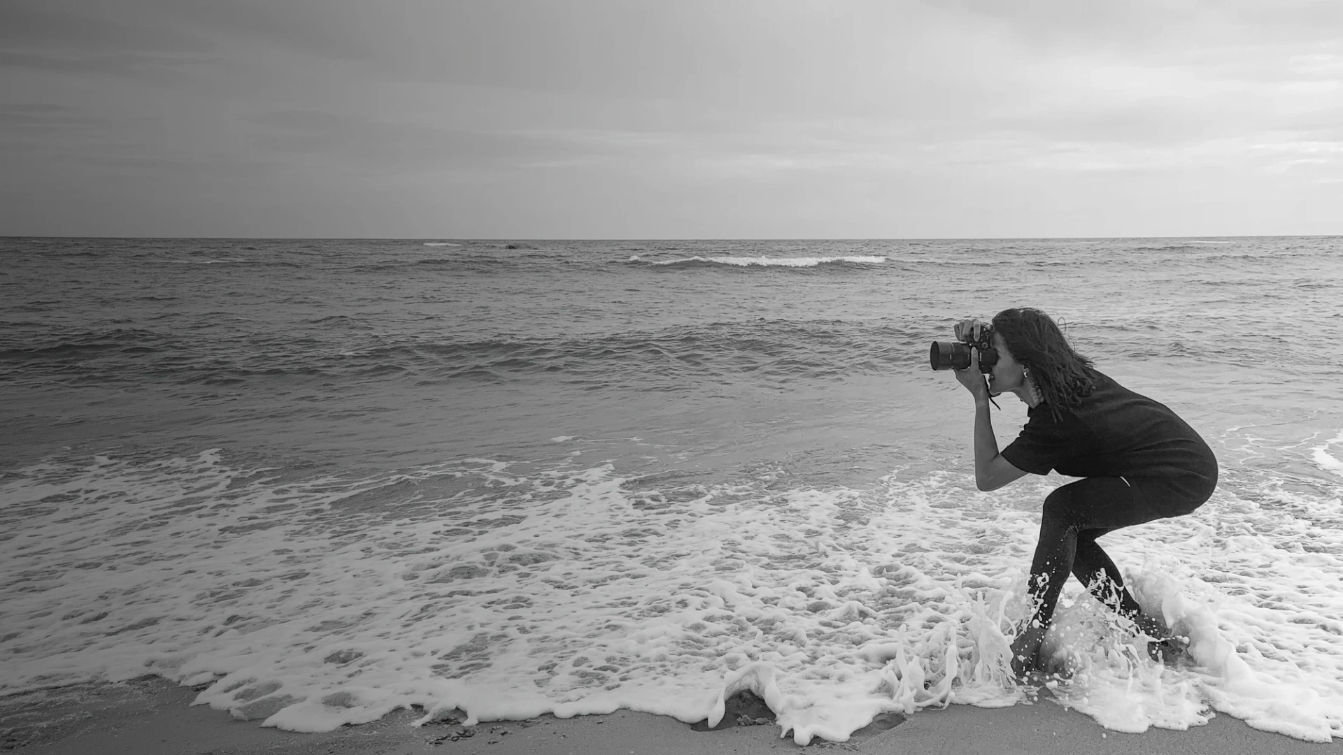 Milena photographing at the edge of the sea in black and white