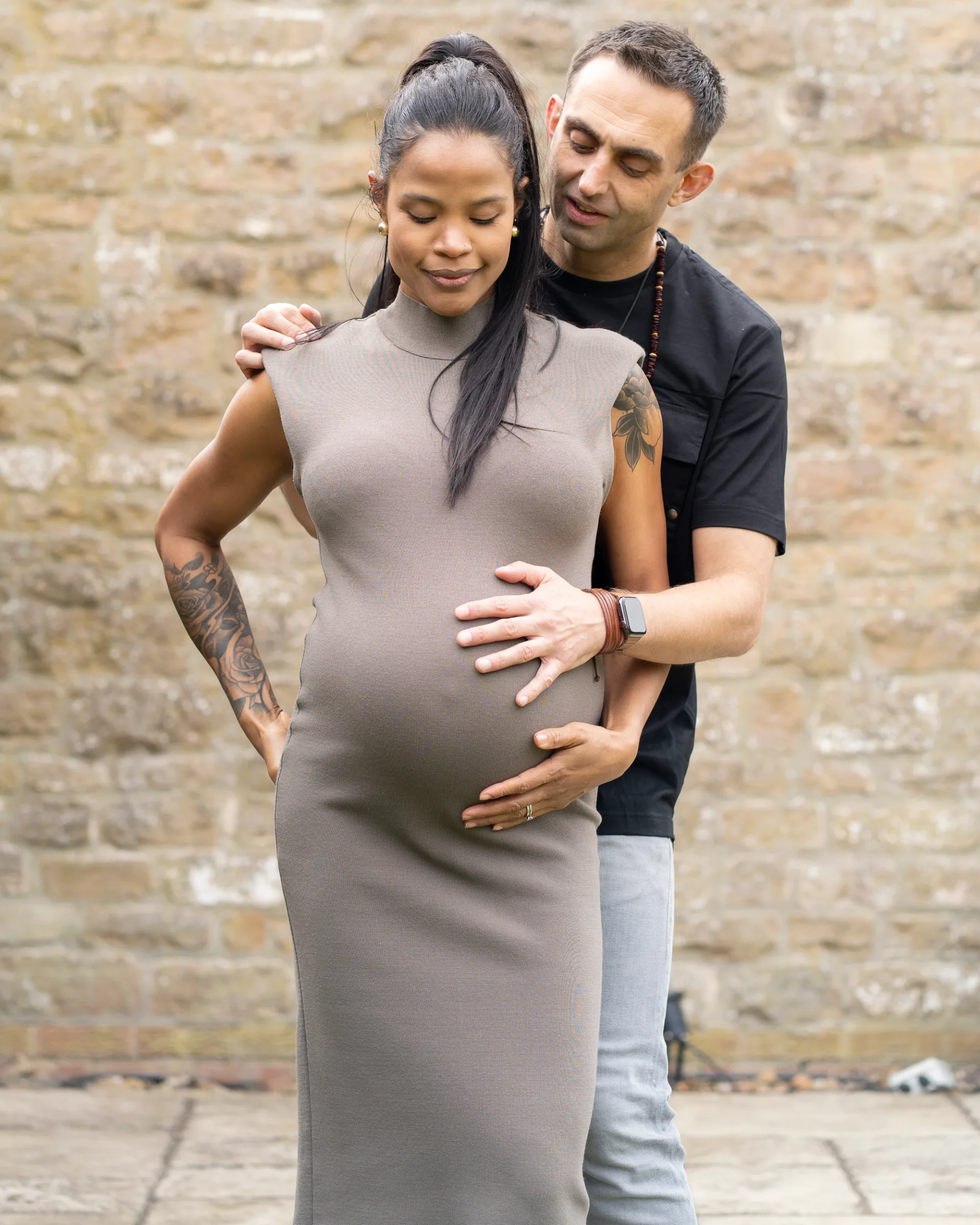 Pregnant woman with husband posing for a photoshoot.