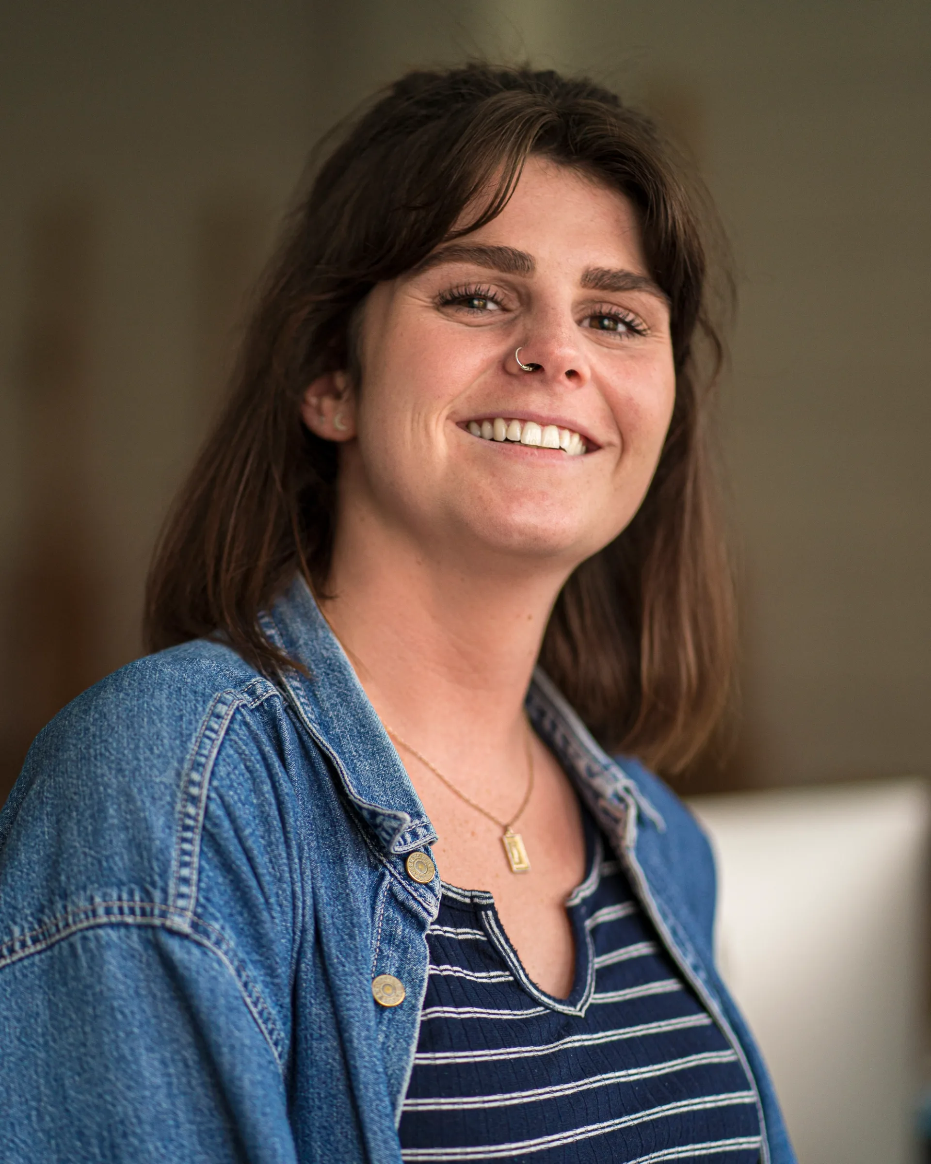Natural light of a smiling woman wearing a denim jacket, with a softly blurred background