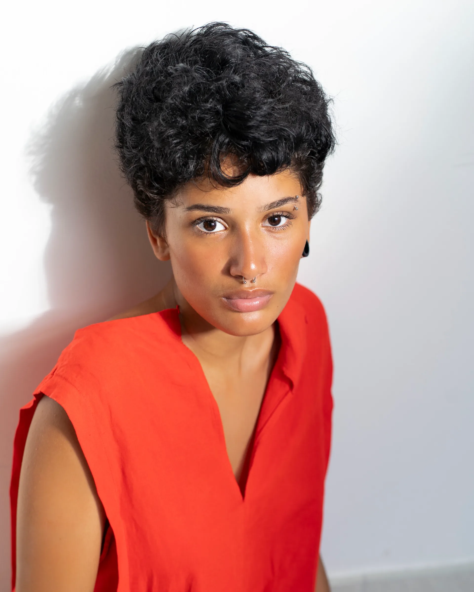 Portrait of a woman with short curly hair wearing a vibrant red top