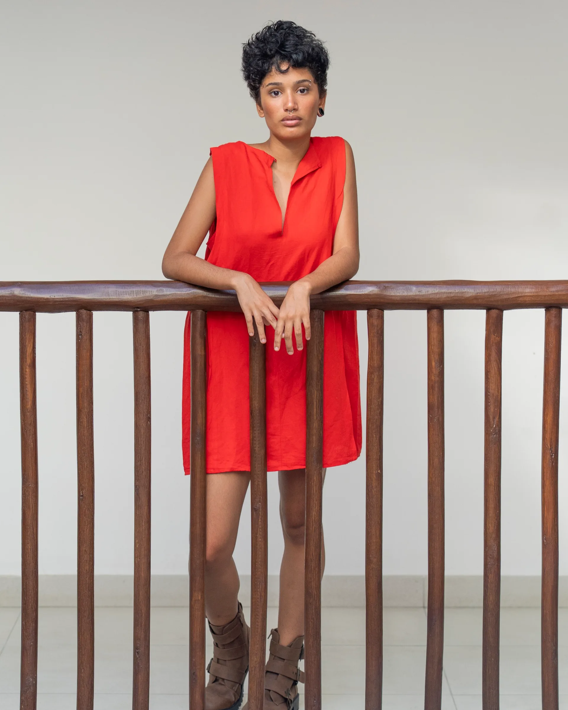 Editorial portrait in a bold red dress, framed by architectural lines with a poised, confident presence