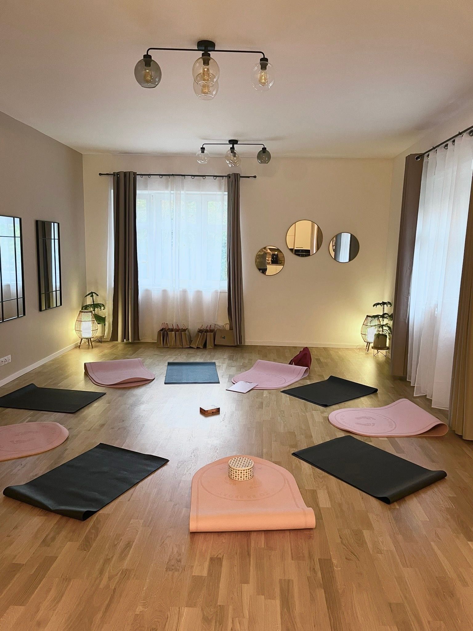 Místnost s cvičebními podložkami rozloženými do kruhu na dřevěné podlaze, připravená na skupinové setkání