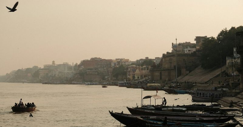 The Varanasi ghats from the Ganges — the 84 stone-stepped bathing and cremation platforms stretch 6.5 kilometres along the western bank; the layered buildings and temples above them represent 1,500 years of construction, with newer structures built directly on top of older ones as the city grew upward rather than outward