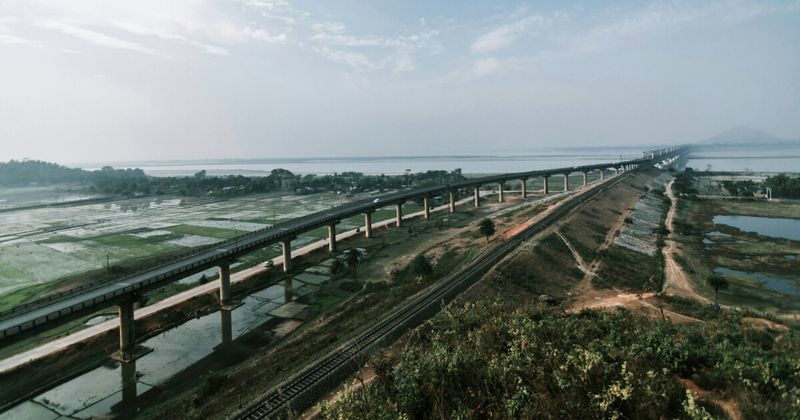 The Brahmaputra river at dawn — the Vivek Express crosses the 4.94km Bogibeel Bridge over the Brahmaputra at approximately 5am; Sleeper ₹1,140 full route.