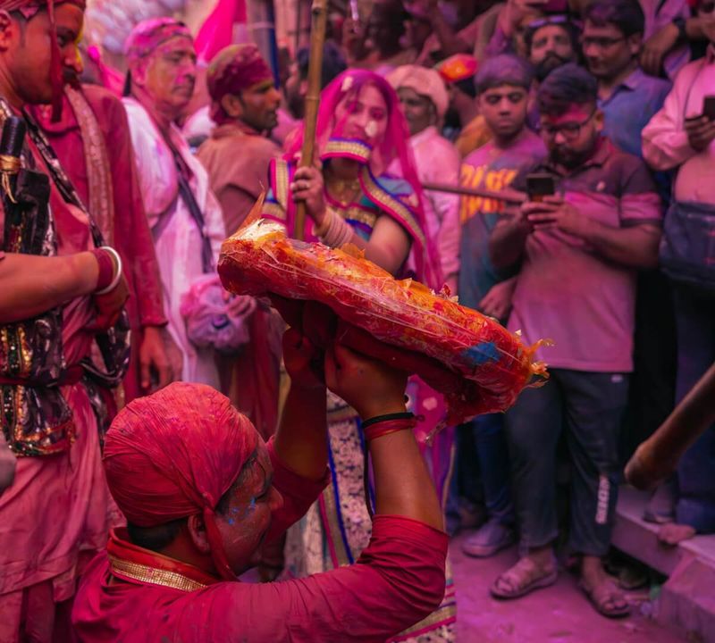 Lathmar Holi in Barsana, Uttar Pradesh — women playfully beat men from Nandgaon with long wooden sticks in a re-enactment of the Krishna-Radha legend; occurs approximately 5–6 days before the main Holi date; one of the most distinctive festival traditions in India