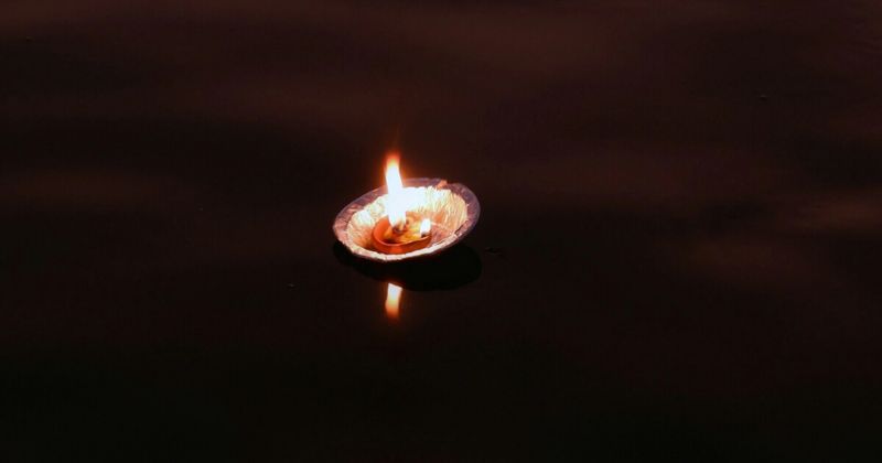Diyas floating on the Ganges at Varanasi after the Ganga Aarti — the earthen oil lamps released by pilgrims and visitors move downstream together in the dark; the ritual of floating a diya on the Ganges is both a votive offering and a symbolic release, the flame continuing to burn until the current carries it beyond sight