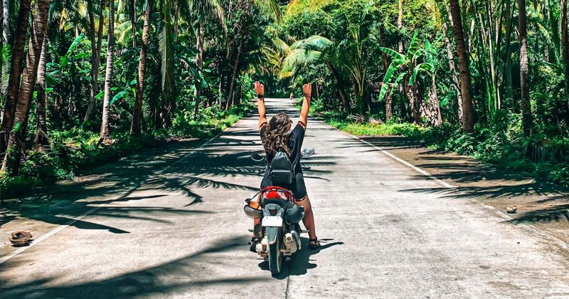 Scooter riding on a palm-lined road in Goa — renting a scooter is the most flexible way to reach Goa's quieter corners, with rentals from ₹300 per day