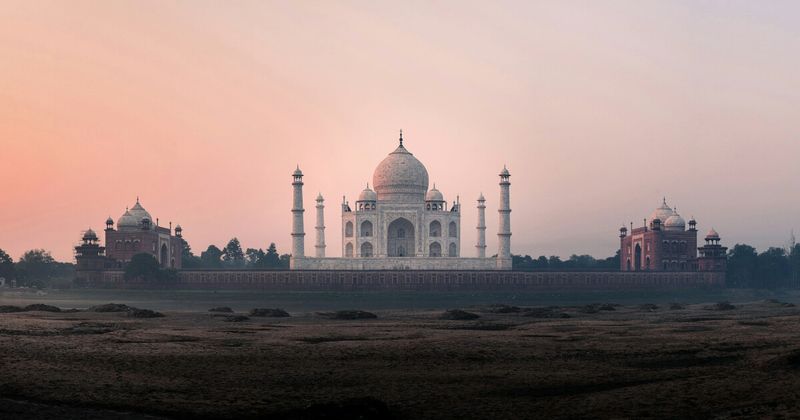 The Taj Mahal at sunset viewed from Mehtab Bagh across the Yamuna River — the garden directly opposite the monument offers the cleanest sunset silhouette view in Agra; foreigner entry ₹300, uncrowded, and the photograph most professional photographers use over the standard garden-pool shot