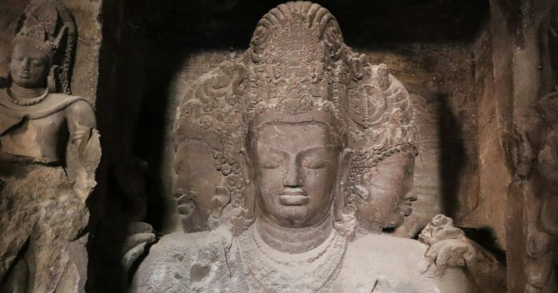 The Trimurti at Elephanta Caves on Elephanta Island near Mumbai — the 6-metre three-faced Shiva (creator, preserver, destroyer) carved into the basalt rock between the 5th and 8th centuries CE; foreigners ₹600; ferry ₹100–₂00 roundtrip from Gateway of India; closed Mondays