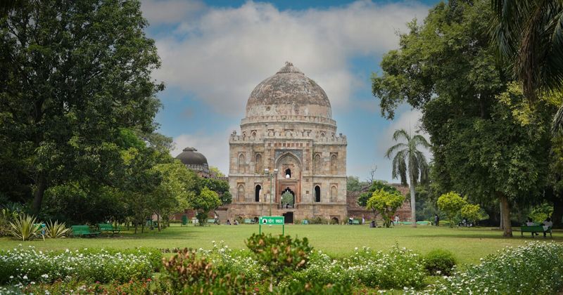 Sheesh Gumbad tomb in Lodhi Garden, Delhi — the 15th-century Lodi dynasty mausoleum with surviving blue-grey glazed tile fragments sits freely accessible among flowerbeds and jogging paths in a 90-acre public park; free entry, open 6am daily