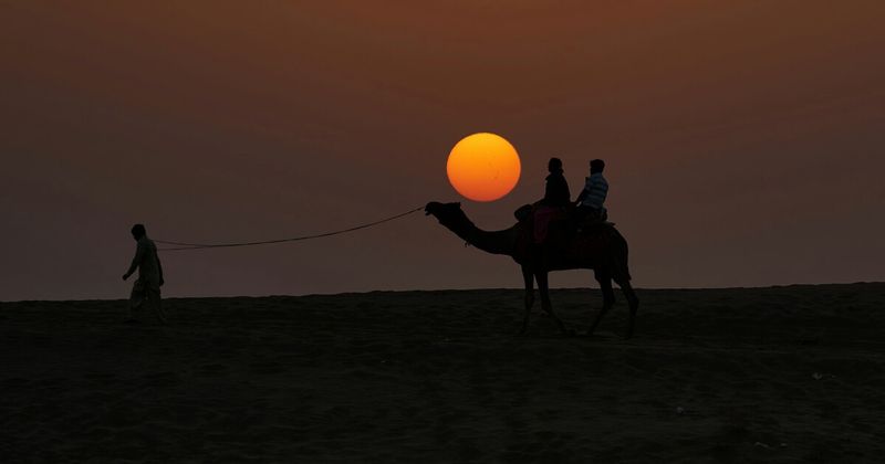 Sam Sand Dunes at sunset west of Jaisalmer — the Thar Desert's most accessible great dunes, 42 kilometres from the city; overnight camp packages from ₹2,500–₄,750 per person include camel ride, folk music, dinner and breakfast; the Milky Way is visible from the camp on clear nights