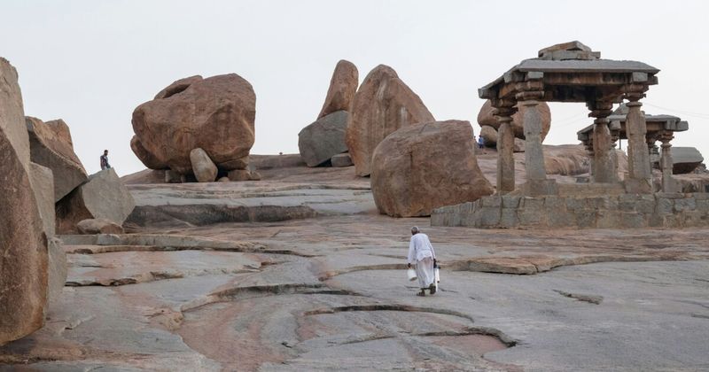 Hampi's granite boulder landscape with Vijayanagara ruins — the orange-pink granite boulders are estimated to be 2.5–3 billion years old; the Vijayanagara architects built their temples among rather than despite these formations; the 26 sq km UNESCO site contains over 1,600 surviving monuments