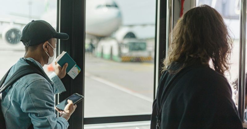 Traveller using FlyFlick flight search on phone at LAX airport — best time to book LAX to India 2026