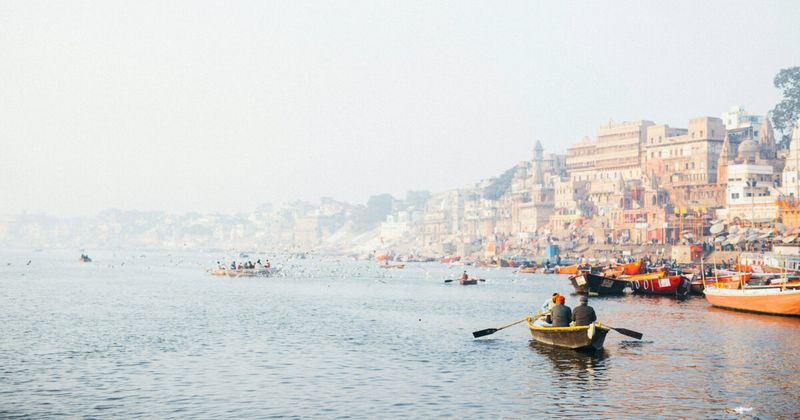 Wooden rowboats on the Ganges river at Varanasi with temple ghats behind — one month India slow travel itinerary Week 1