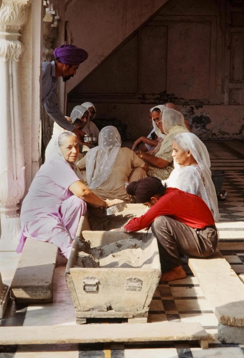 The langar hall at the Golden Temple in Amritsar — the community kitchen feeds 50,000–100,000 people every day for free, 24 hours a day, without discrimination of religion, caste, or background; sitting on the floor in rows is called 'pangat' and is a deliberate act of equality — even the most prominent visitor eats on the same floor as the most ordinary