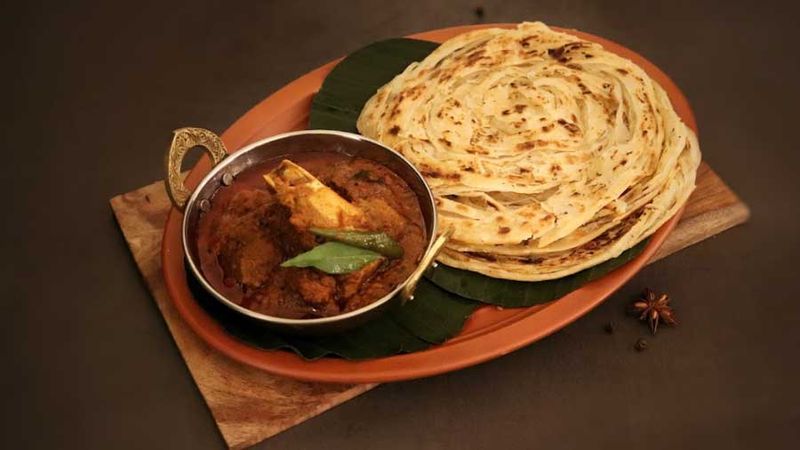 Flaky Malabar Parotta with meat curry on a banana leaf