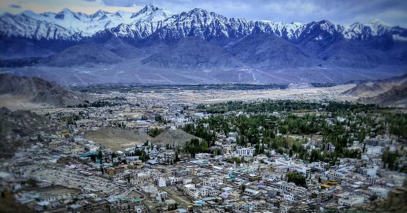 Leh town from above — the capital of Ladakh sits at 3,524 metres in a high-altitude valley surrounded by bare Himalayan peaks, and requires two full days of acclimatization before any high-altitude driving can safely begin