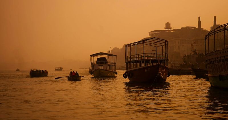 Varanasi ghats at dawn from the Ganges — the full 84-ghat riverfront in pre-sunrise light, accessible by shared boat from ₹200–₹400 per person or private boat from ₹800–₁,500; the most-cited experience in any honest account of the city