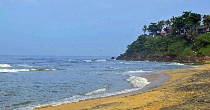 Varkala's 15-metre red laterite cliff above Papanasam Beach on the Arabian Sea coast of Kerala — the cliff-top restaurant and guesthouse strip gives travellers a unique elevated view of the beach below