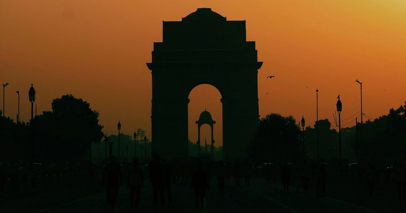India Gate at sunset in New Delhi — the 43-metre All India War Memorial arch built in 1931 commemorates 70,000 Indian soldiers killed in World War I; free entry, best experienced at golden hour when the sandstone turns orange and Delhi's residents fill the surrounding lawns