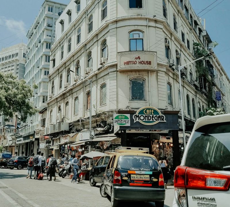 South Mumbai street scene in the Fort/Colaba area — the 19th and early 20th-century colonial architecture and the street life of modern Mumbai coexist in the same frame; this is the most architecturally dense district in India for the Victorian-Gothic-meets-Indian-Saracenic style that defines the city's heritage core